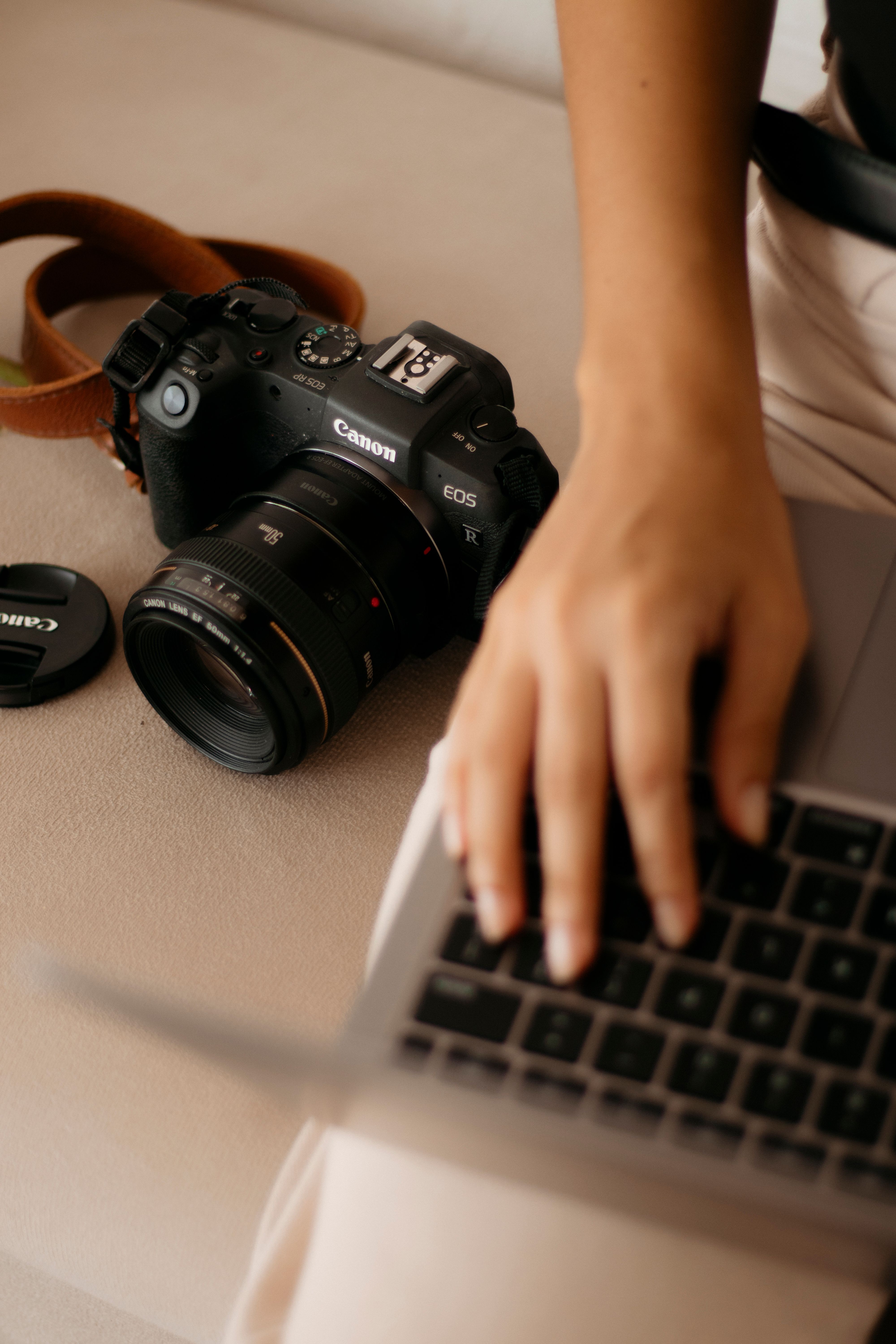 Close-up of a hand on laptop with a DSLR camera, perfect for creative professionals.