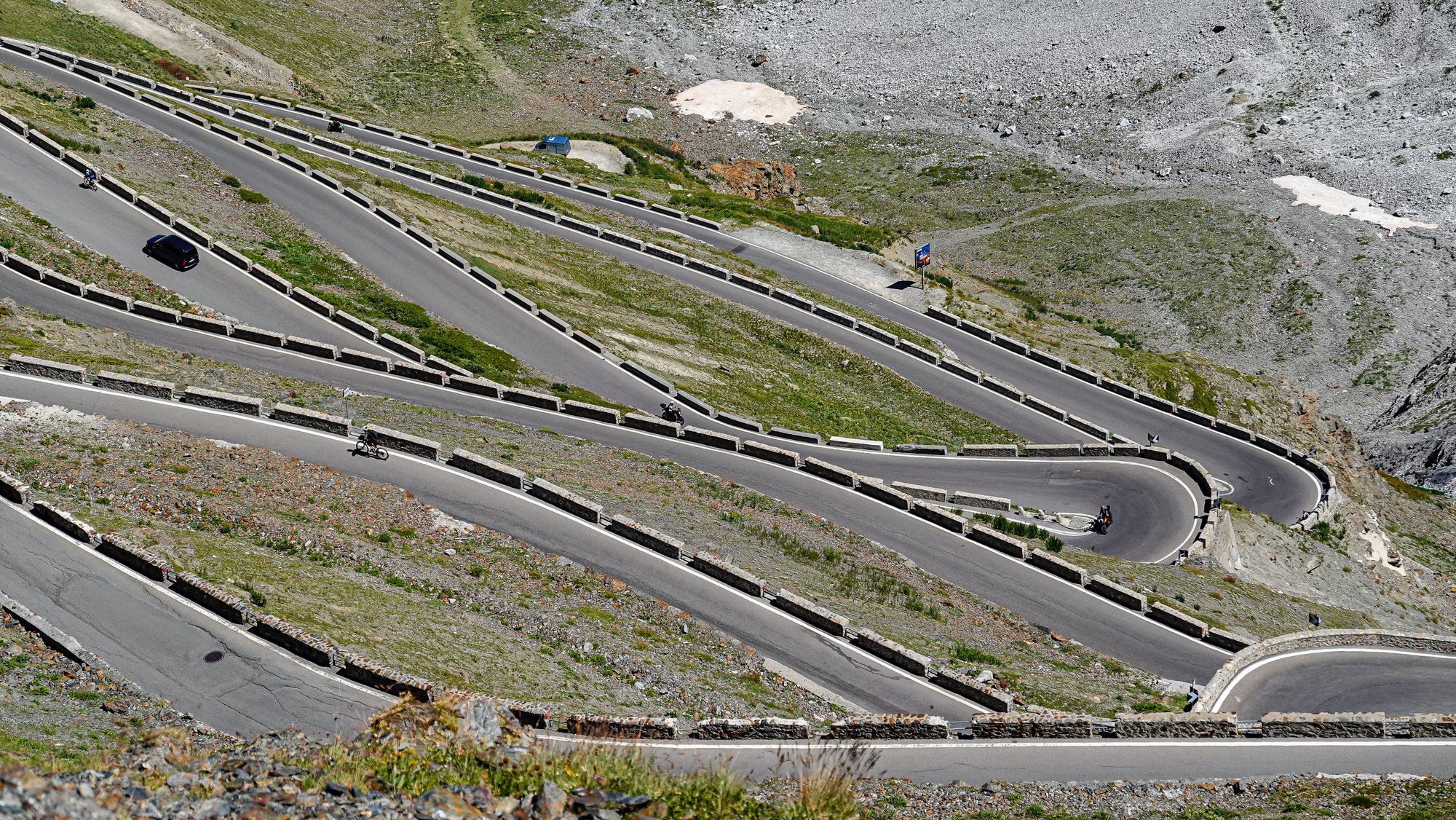 Carretera de montaña con curvas de herradura ascendiendo hacia una cima alpina