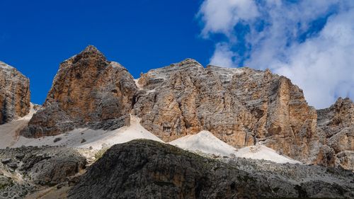 Free Dramatic rocky mountain peaks under a bright blue sky with white clouds. Stock Photo