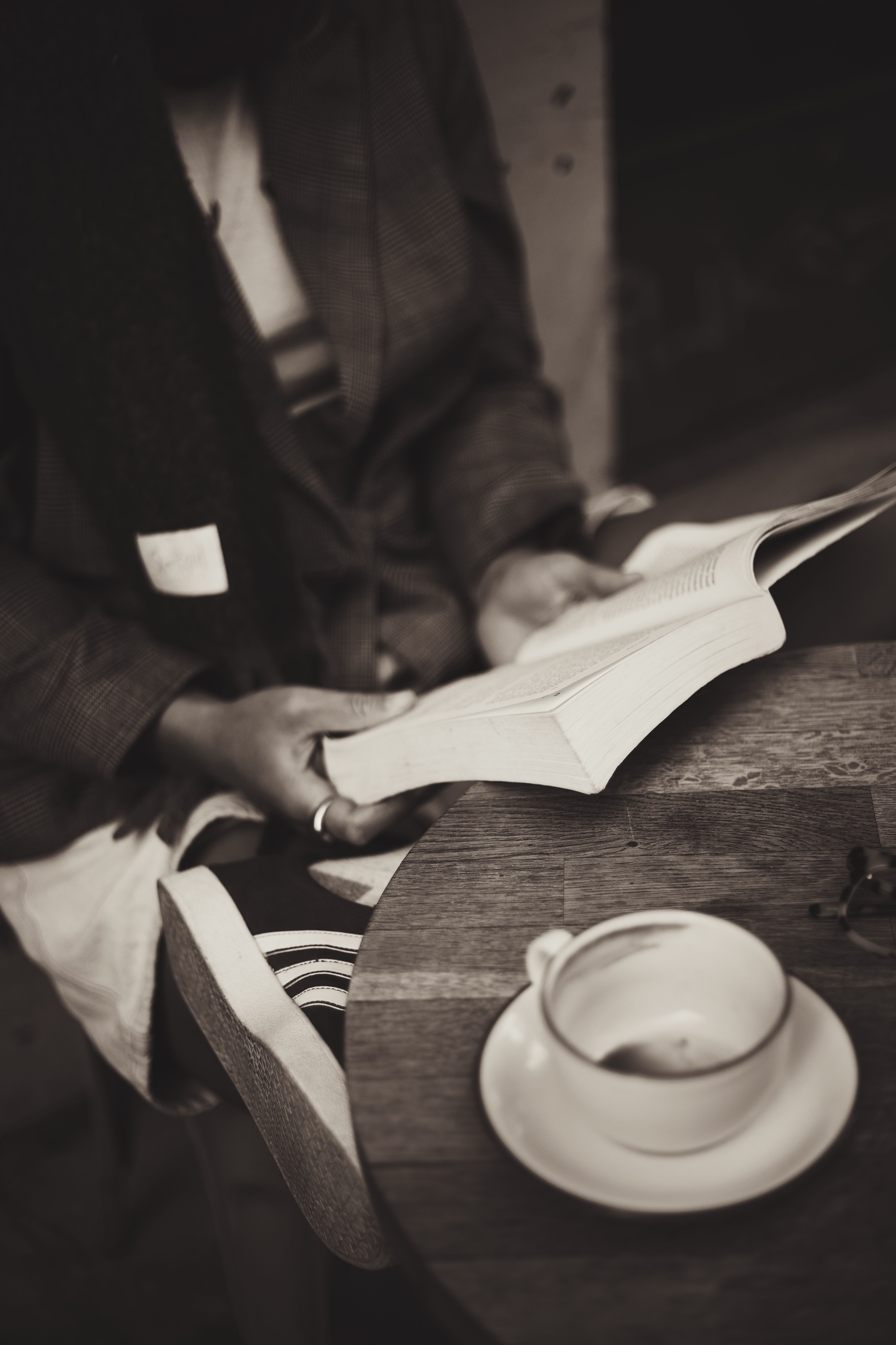 A tranquil scene of a person reading a book alongside a cup of coffee in a cozy cafe.
