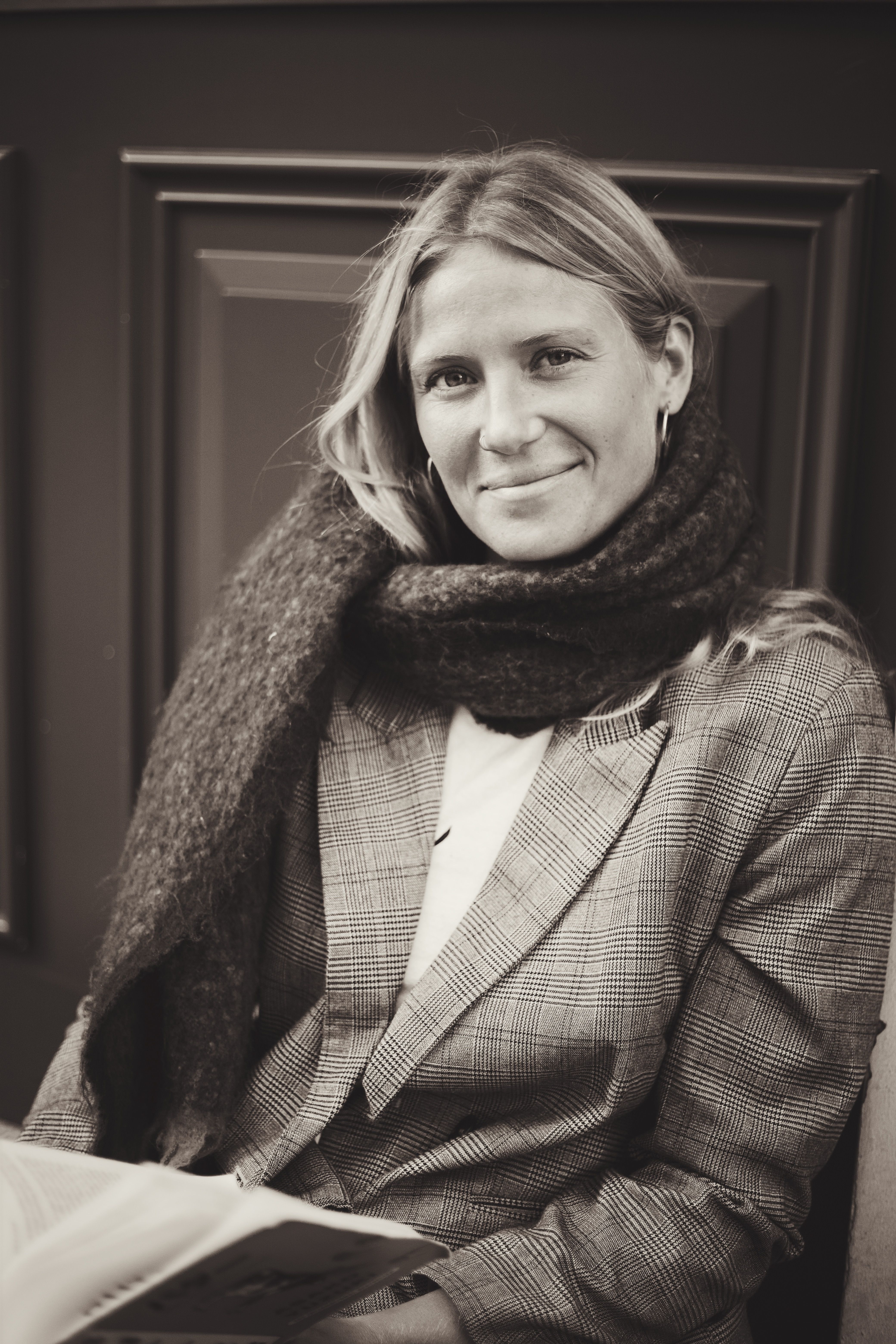 Elegant woman in vintage black and white portrait wearing a plaid jacket and scarf.