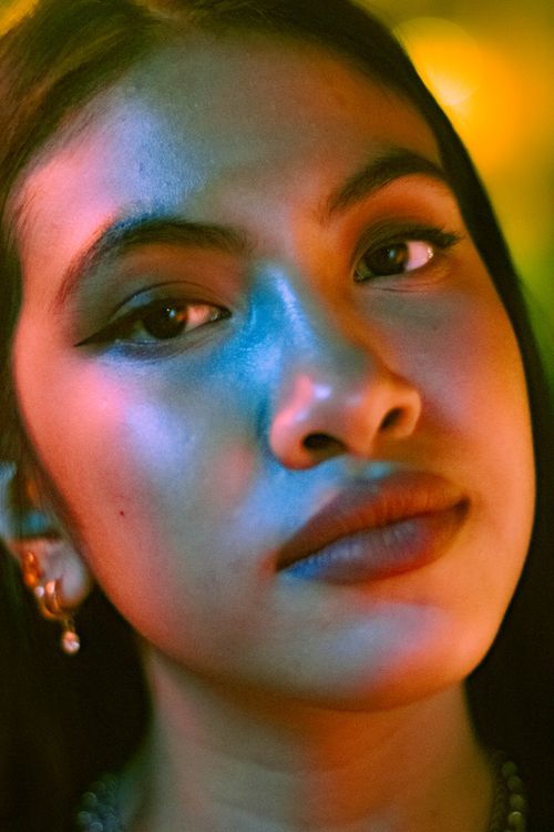 Free Artistic portrait of a woman with colorful lighting, showcasing her serene expression. Stock Photo