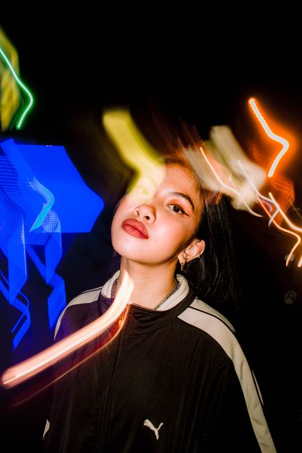 Dynamic night portrait of a woman with colorful light streaks. Captivating long exposure photography.