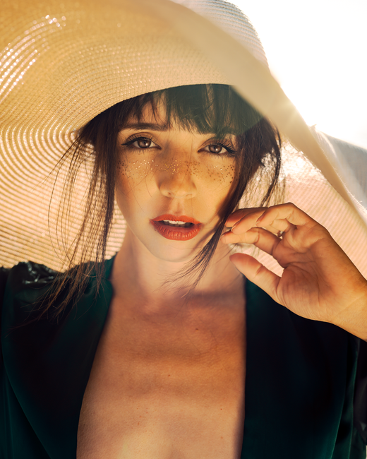 Close-up portrait of a woman with freckles wearing a sun hat, capturing summer vibes.