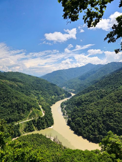Free Stunning aerial view of the Teesta River winding through lush mountain terrain under a blue sky. Stock Photo