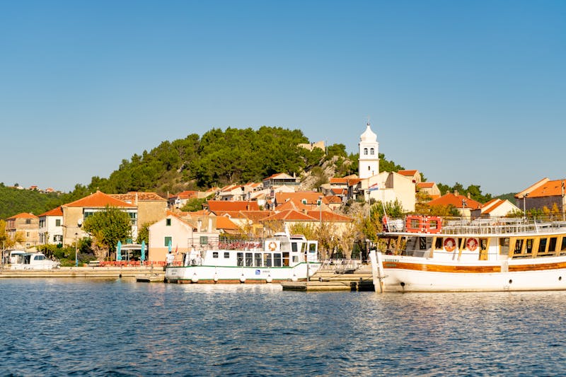 Vue pittoresque du port de Skradin avec bateaux et église sous un ciel d'été clair