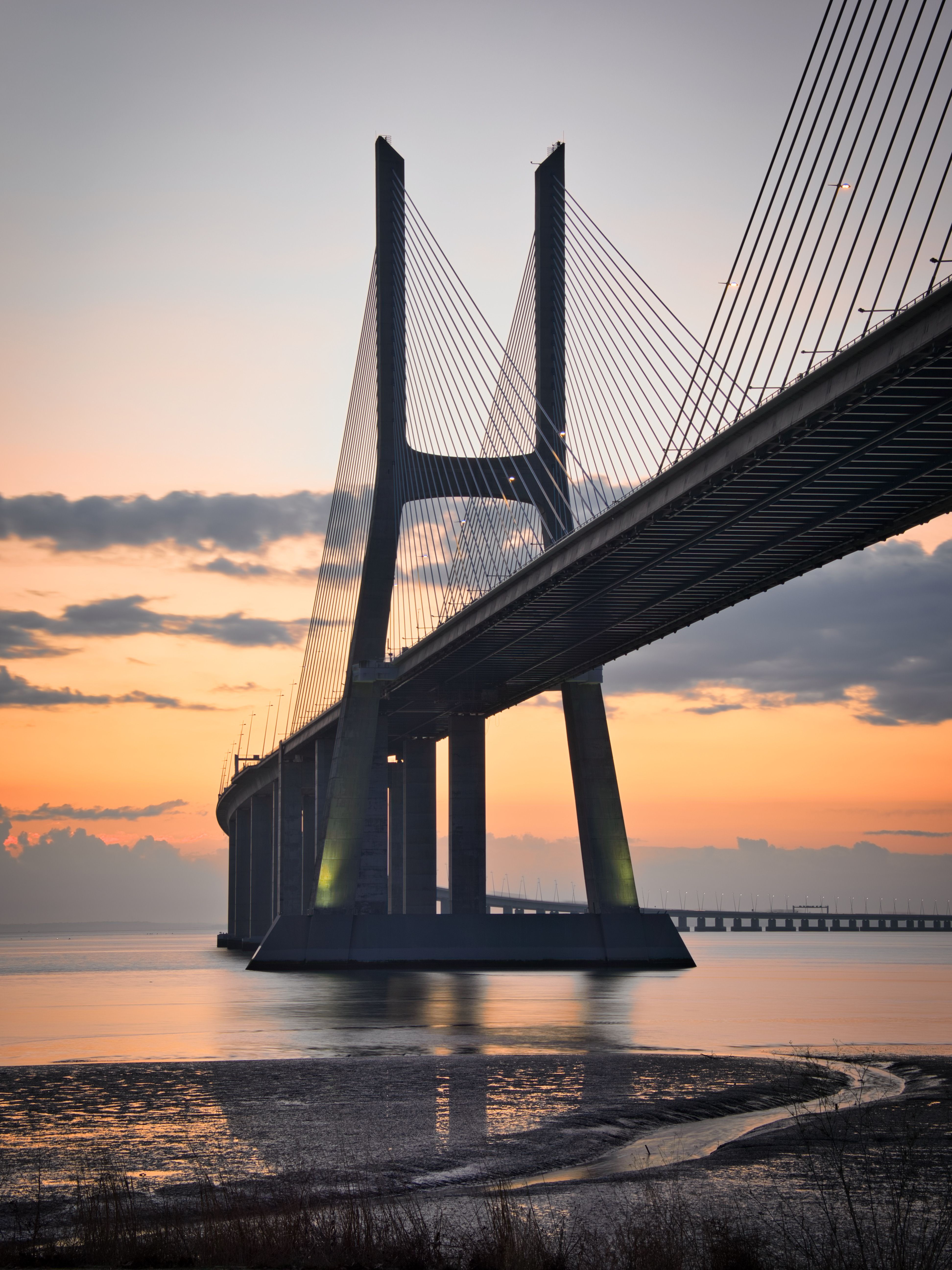 Sunrise view of the Vasco da Gama Bridge stretching across the calm waters.