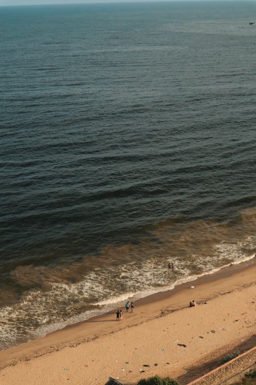 Free Serene aerial shot of a sandy beach with gentle ocean waves under a clear sky. Stock Photo