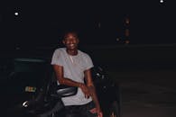 在弗吉尼亚州威廉斯堡，一名男子晚上靠在车上，微笑着，纹身清晰可见