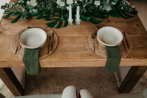 Free Rustic dining table with green decor and elegant place settings for two. Stock Photo