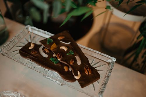Free Artisan chocolate bars with assorted nuts served on a crystal plate, perfect for gourmet indulgence. Stock Photo