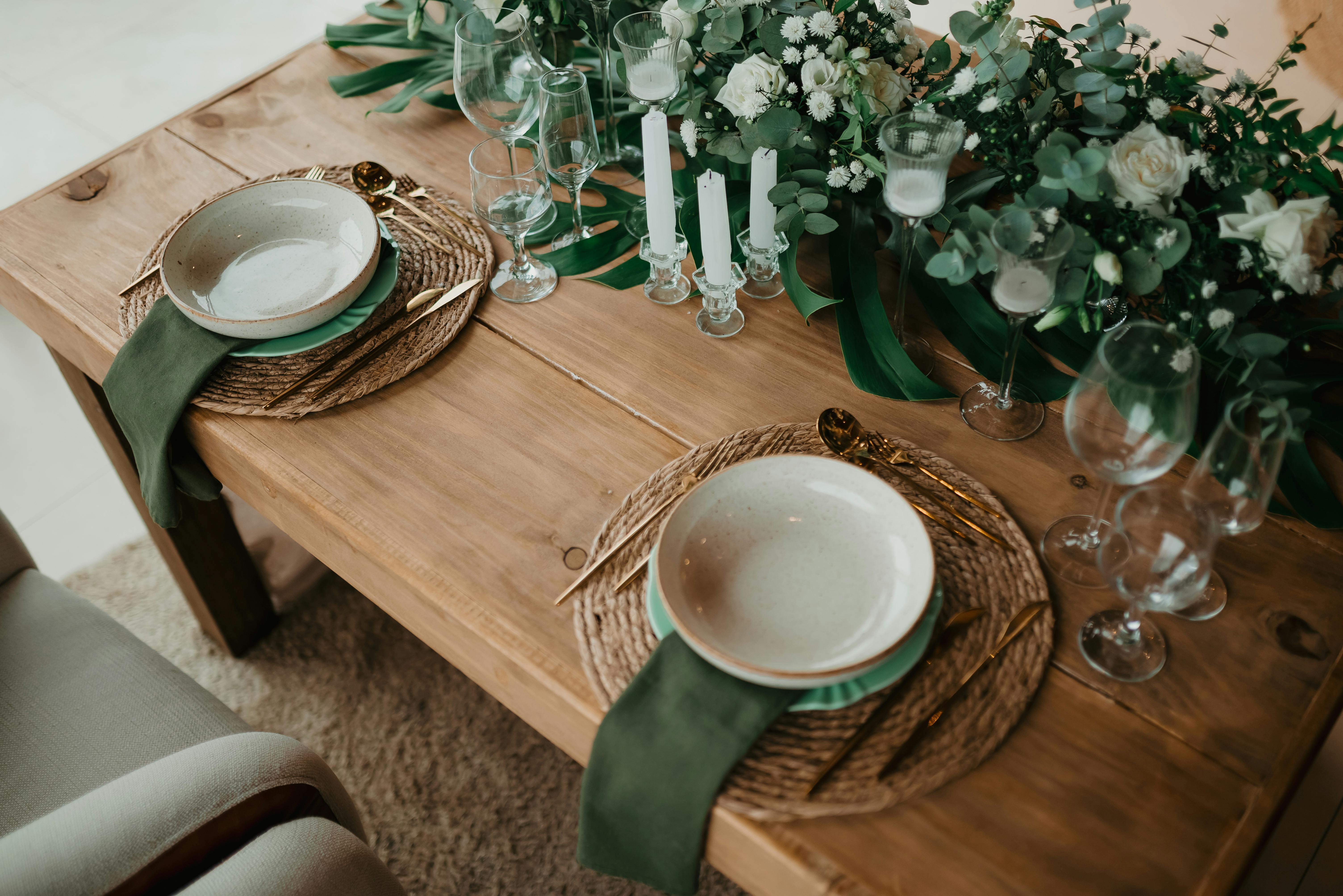 A beautifully arranged rustic dining table with greenery, candles, and tableware.