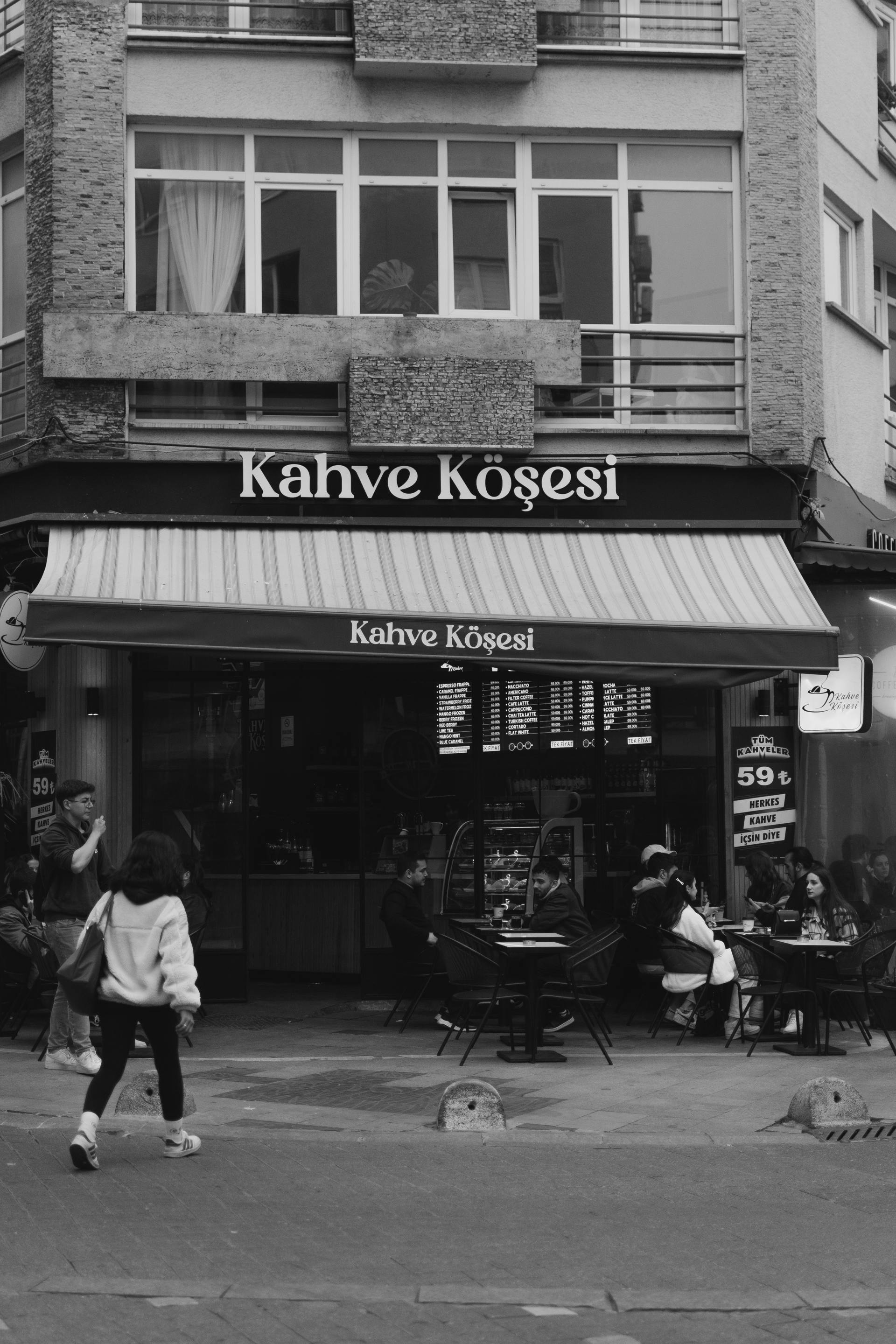 Monochrome street view of a café in Turkey with pedestrians.