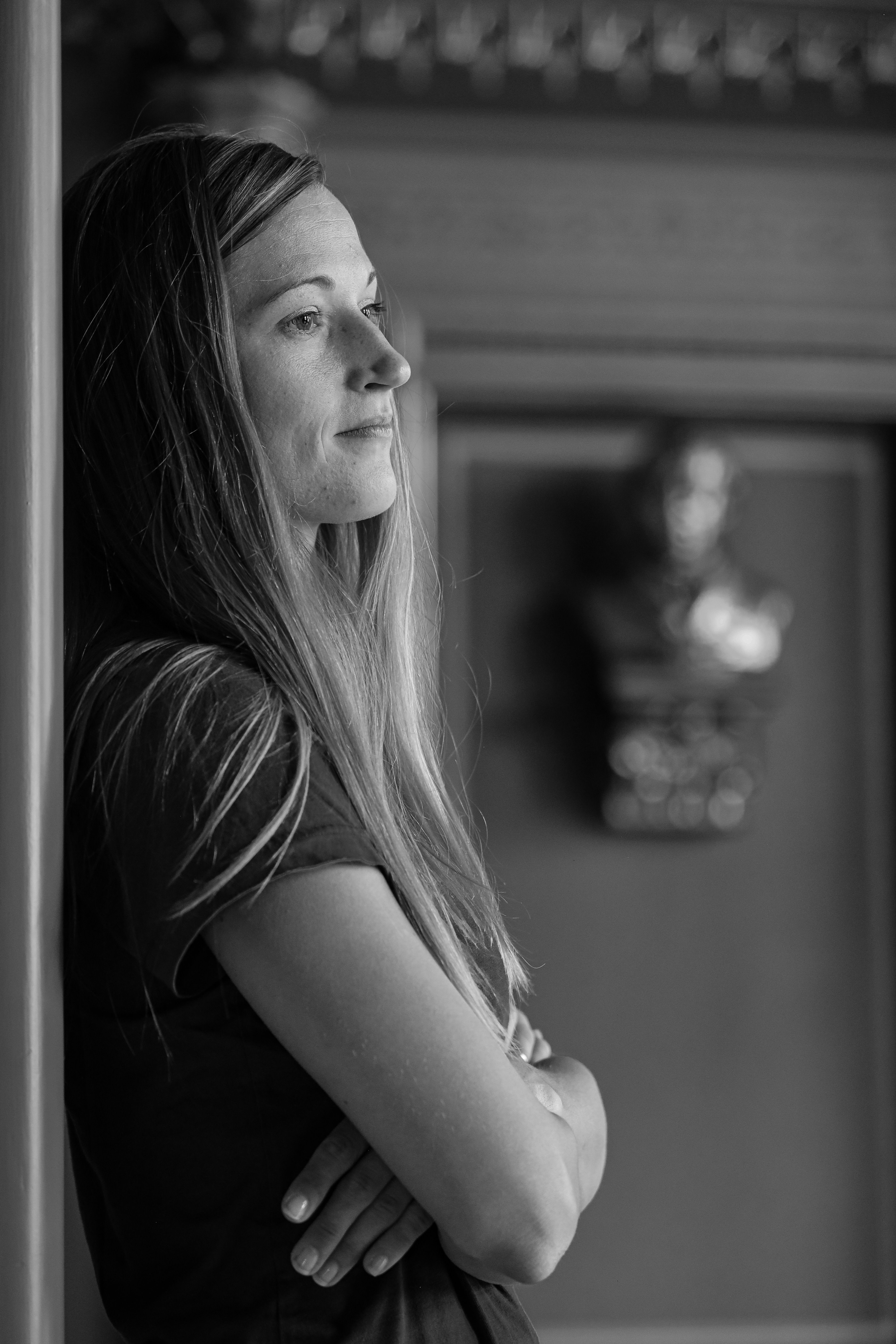 Thoughtful woman leaning indoors, captured in monochrome for a dramatic effect.