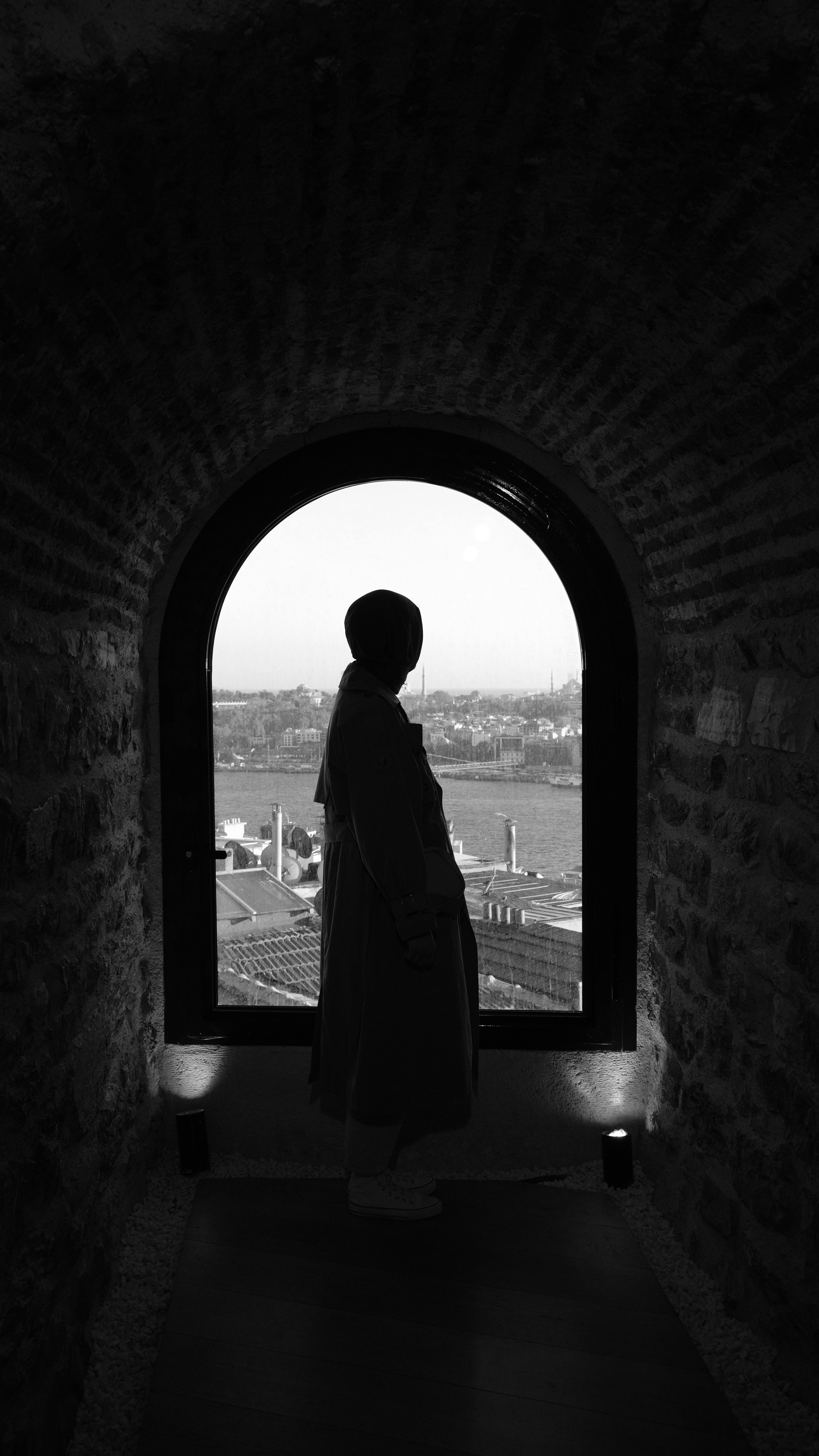 Silhouette view of a cityscape through an arched window in black and white, capturing a mood of contemplation.