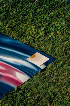 Vibrant yoga mat on grass with a card depicting sunshine, ideal for outdoor exercises.
