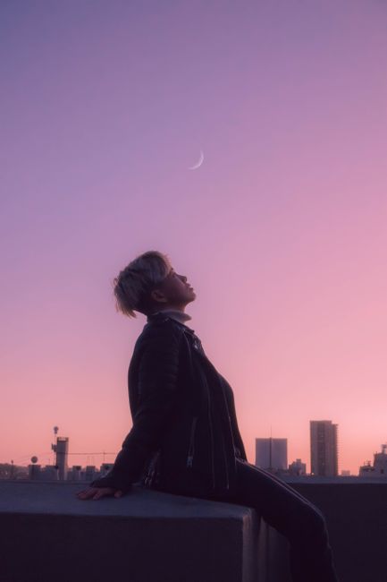 Person gazing at the moon during twilight with San Francisco skyline in the background.