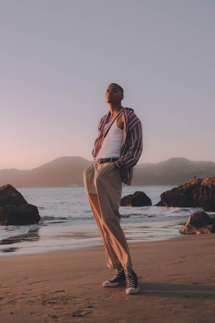 Model poses elegantly on San Francisco beach at sunset, wearing fashionable summer attire.