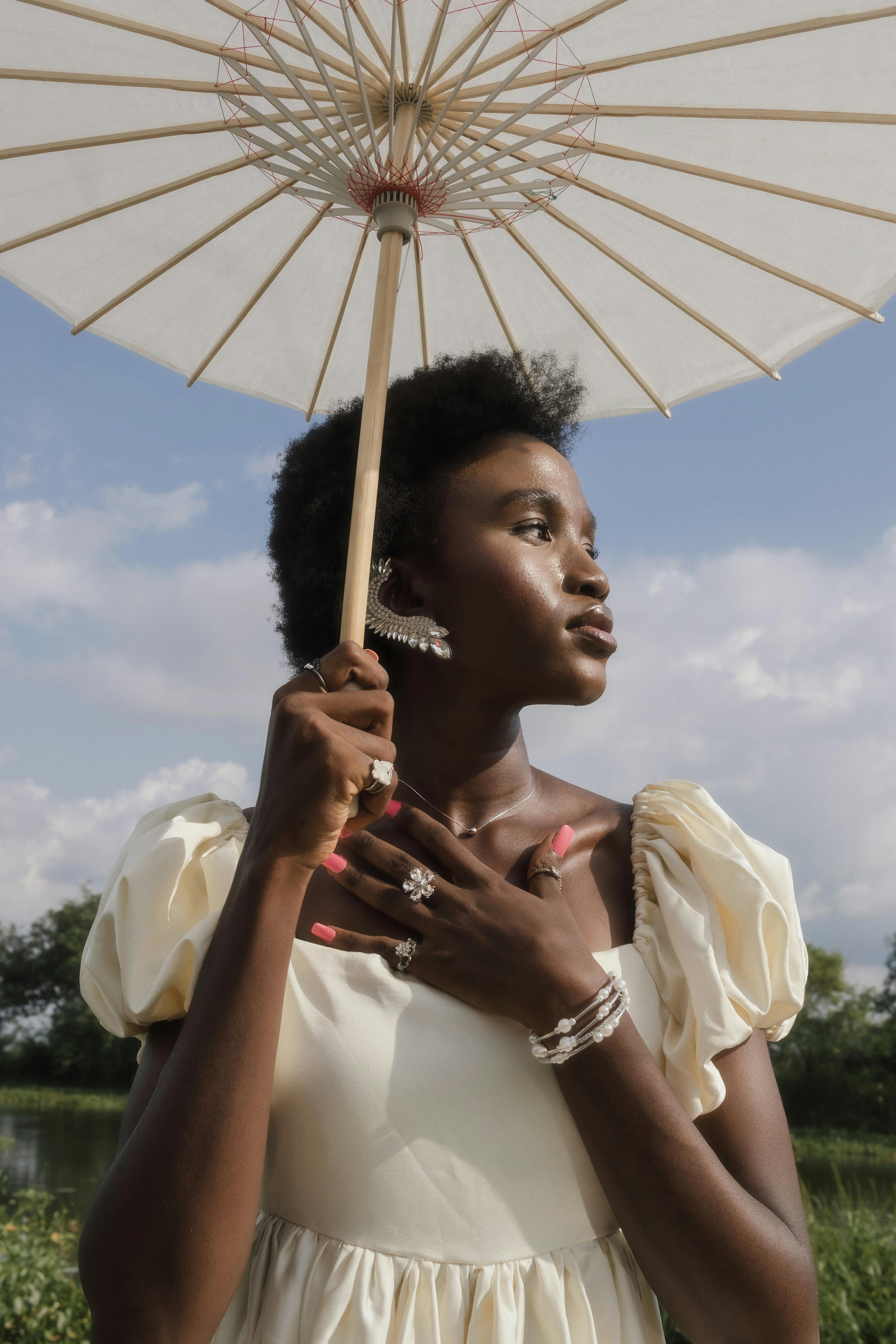 Elegant African woman holding a parasol outdoors, embracing natural beauty.