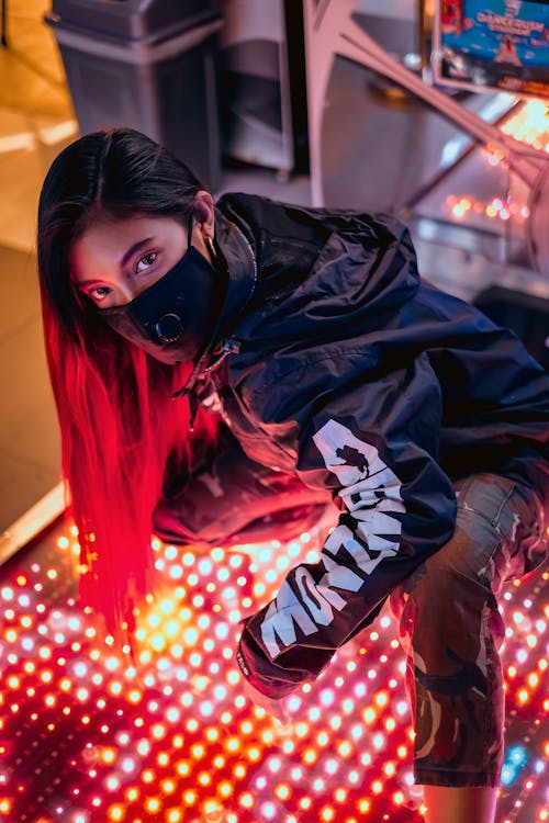 Woman in Face Mask Kneeling on Lit up Floor Panel