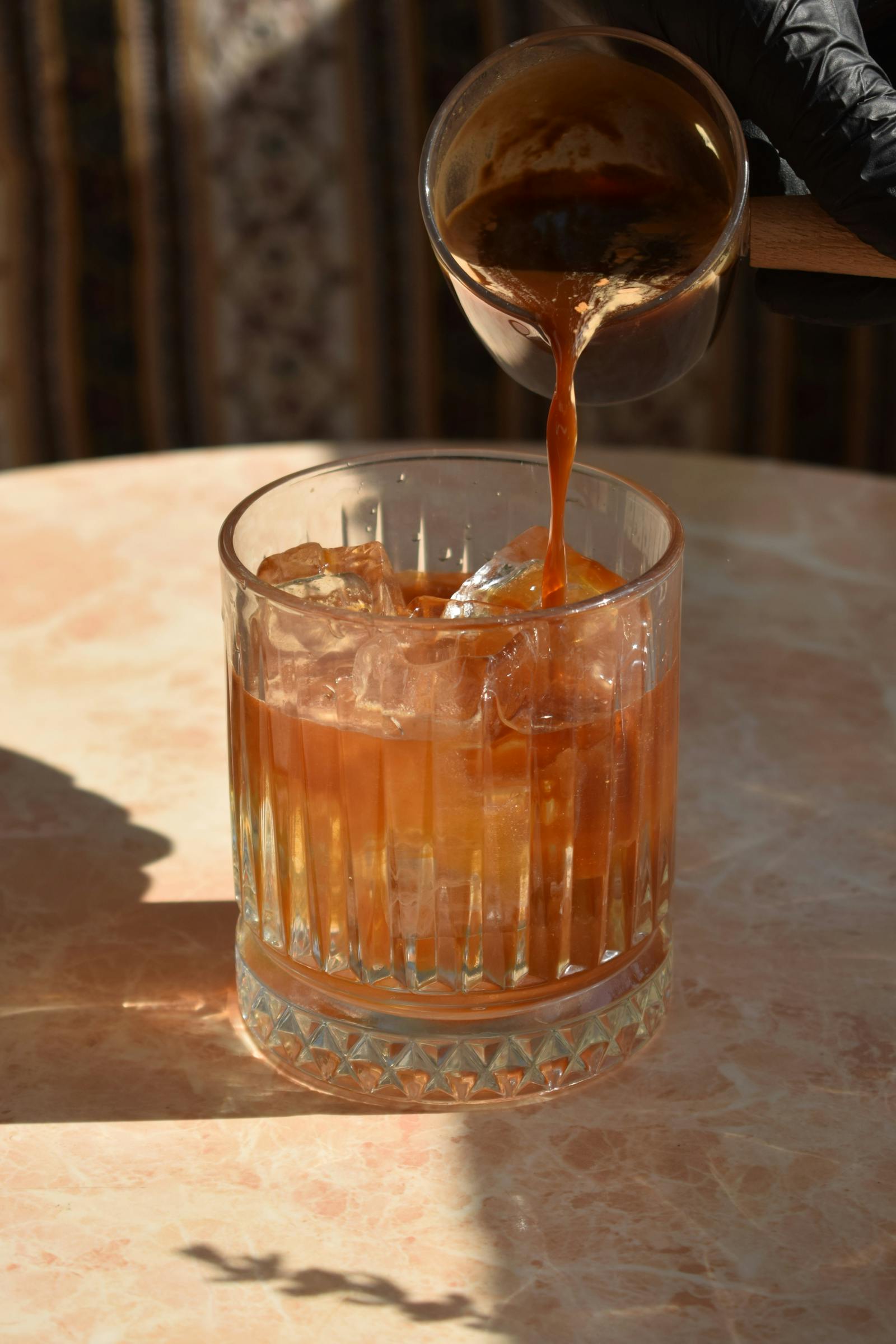 Iced coffee in glass with ice and espresso pouring in