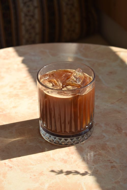 Free A refreshing iced coffee in a faceted glass on a sunlit marble table. Stock Photo