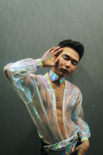 Model posing in a translucent, iridescent outfit displaying futuristic fashion trends.