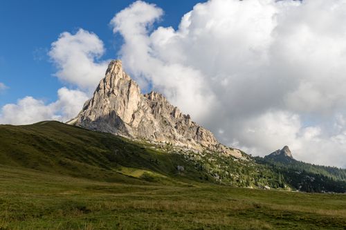 Free A breathtaking view of the Dolomites mountain range in Italy with lush green grass and a clear blue sky. Stock Photo