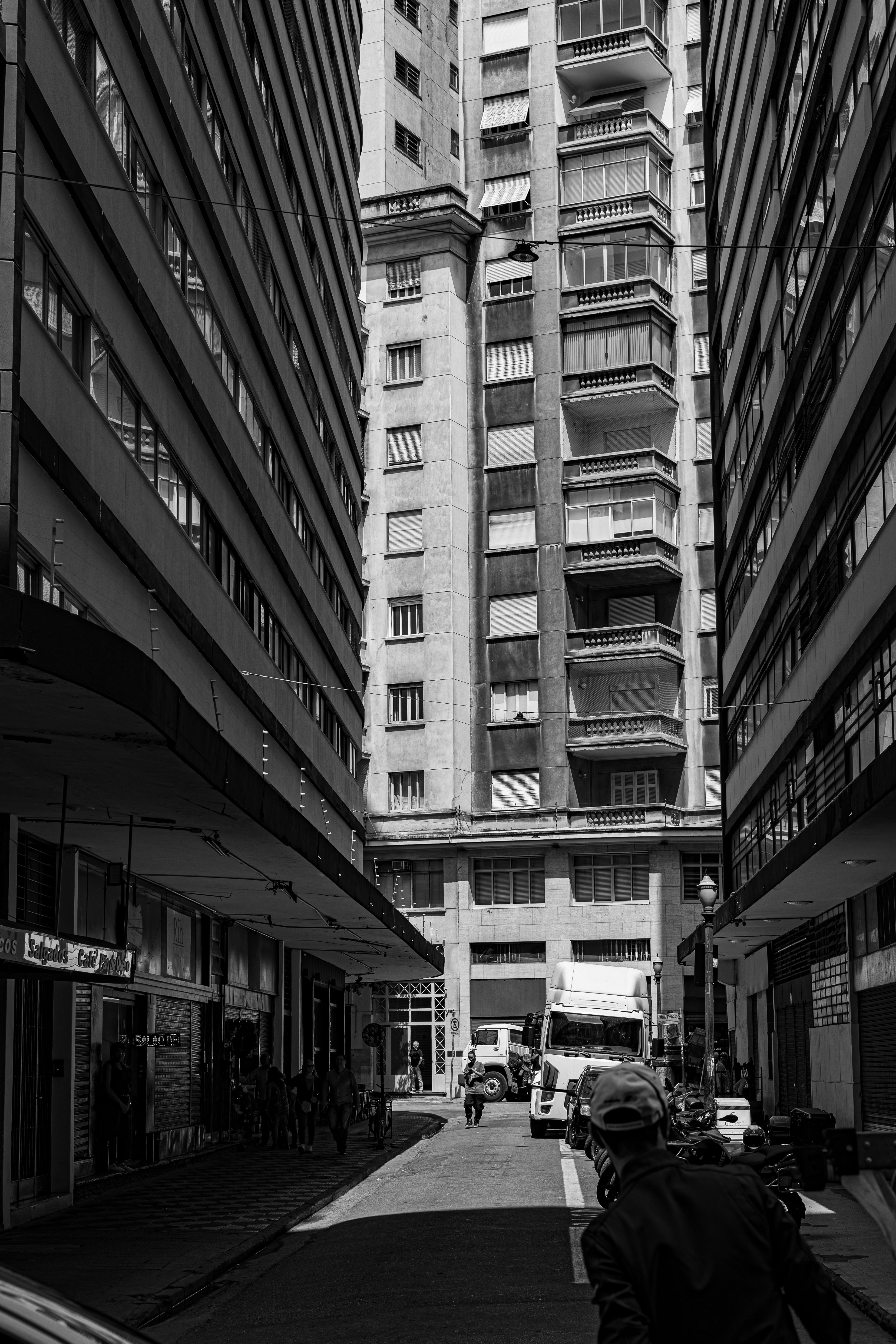 Fotomural Fotografía en blanco y negro de un callejón urbano entre edificios altos.