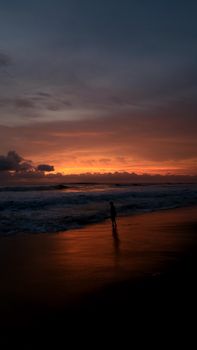 A tranquil beach sunset scene with a lone silhouette creating a peaceful atmosphere.