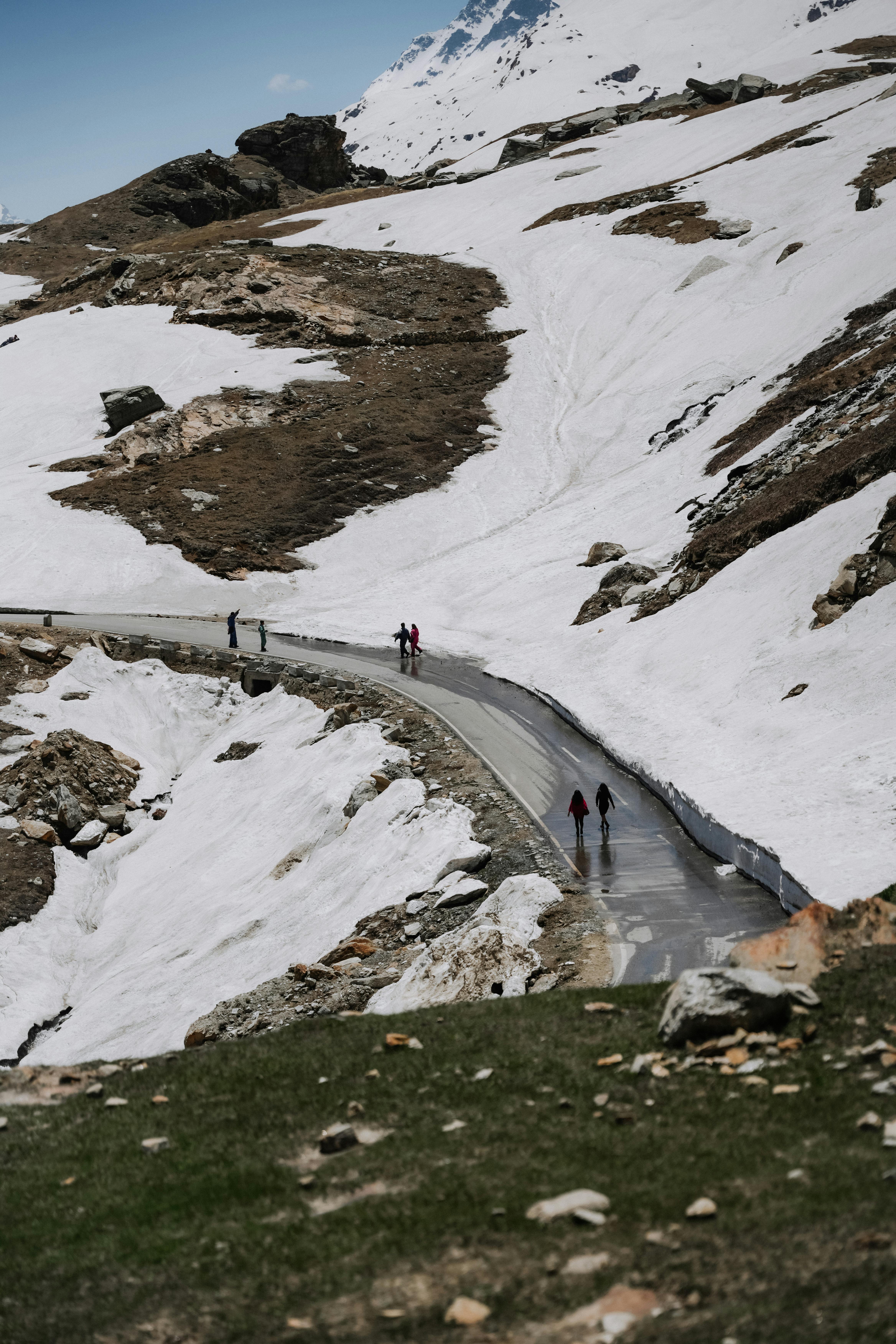 A winding road through a snowy mountain landscape with people walking. Ideal for travel and adventure themes.