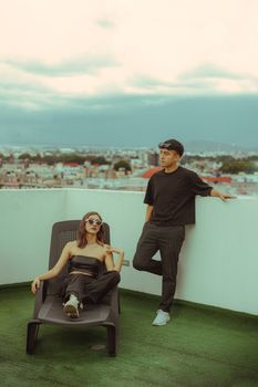 Young adults enjoying a relaxed moment on a modern rooftop with cityscape view.