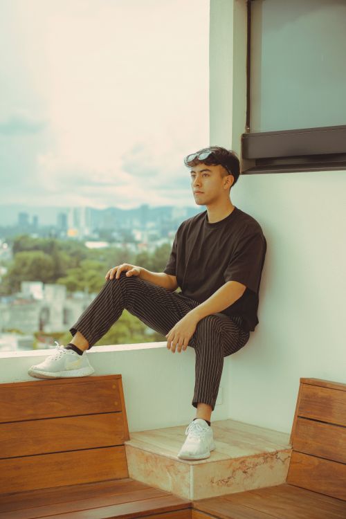 Young Man Relaxing on Rooftop in Casual Attire · Free Stock Photo