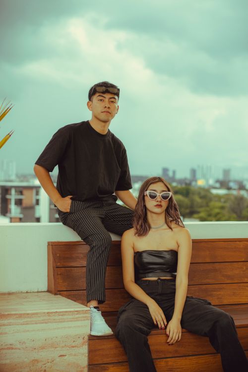 Free Stylish young adults enjoying a casual day on a rooftop with urban backdrop. Stock Photo