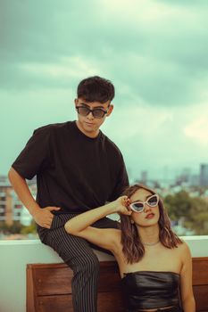 Trendy young adults in sunglasses relaxing on an urban rooftop, exuding a stylish and carefree vibe.