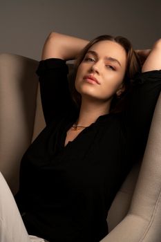 Casual portrait of a young woman with a relaxed pose, arms above head.