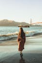一名女子沿着风景优美的海滩散步，金门大桥就在眼前，捕捉到了宁静的时刻