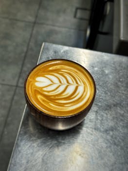 Beautifully crafted latte art in a wooden cup with a leaf pattern.