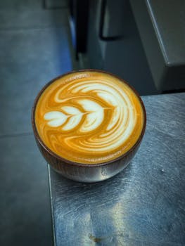 A beautifully crafted latte art in a wooden cup on a steel countertop.
