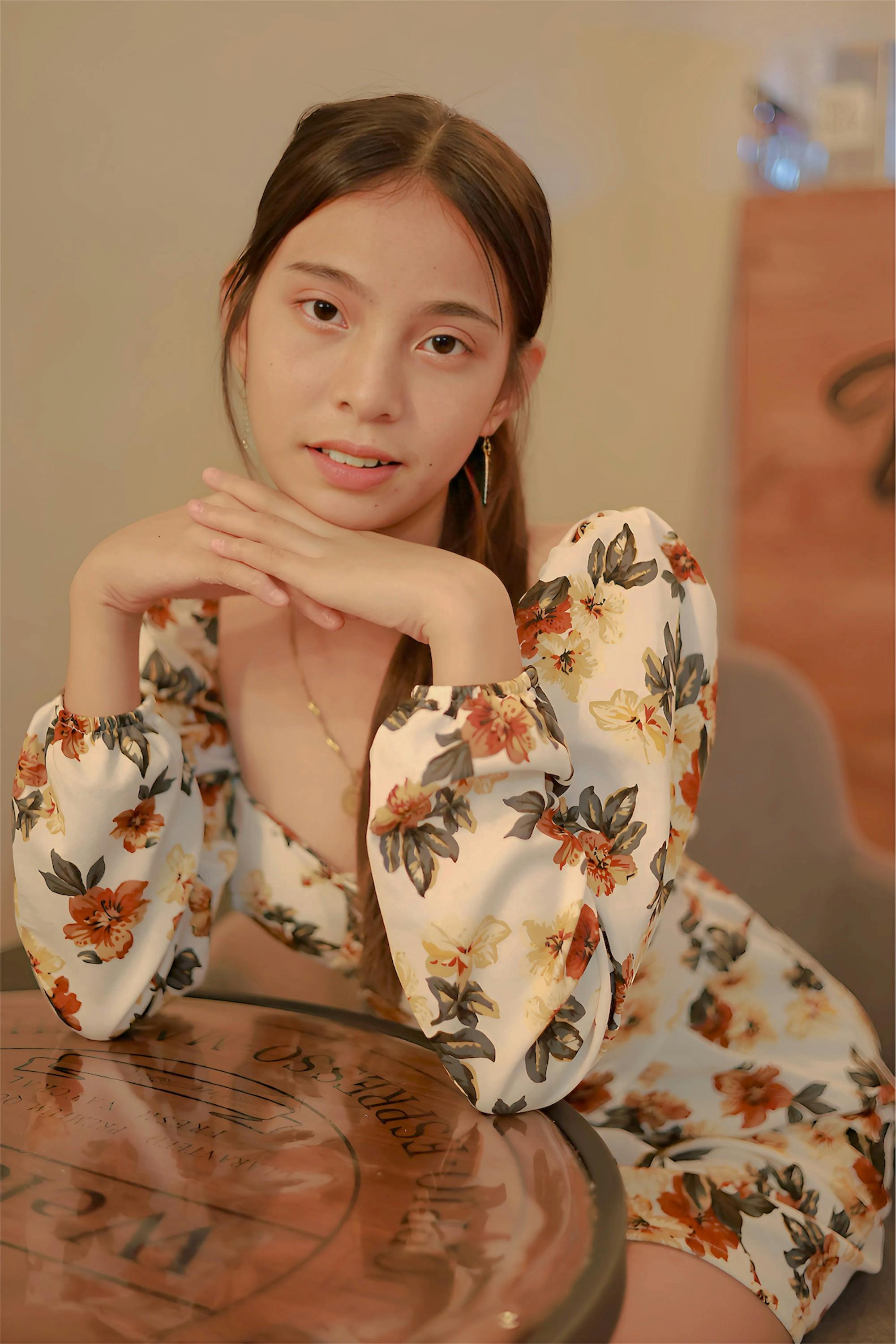 Безкоштовне Молода жінка в квітковій сукні позує в приміщенні стокове фото