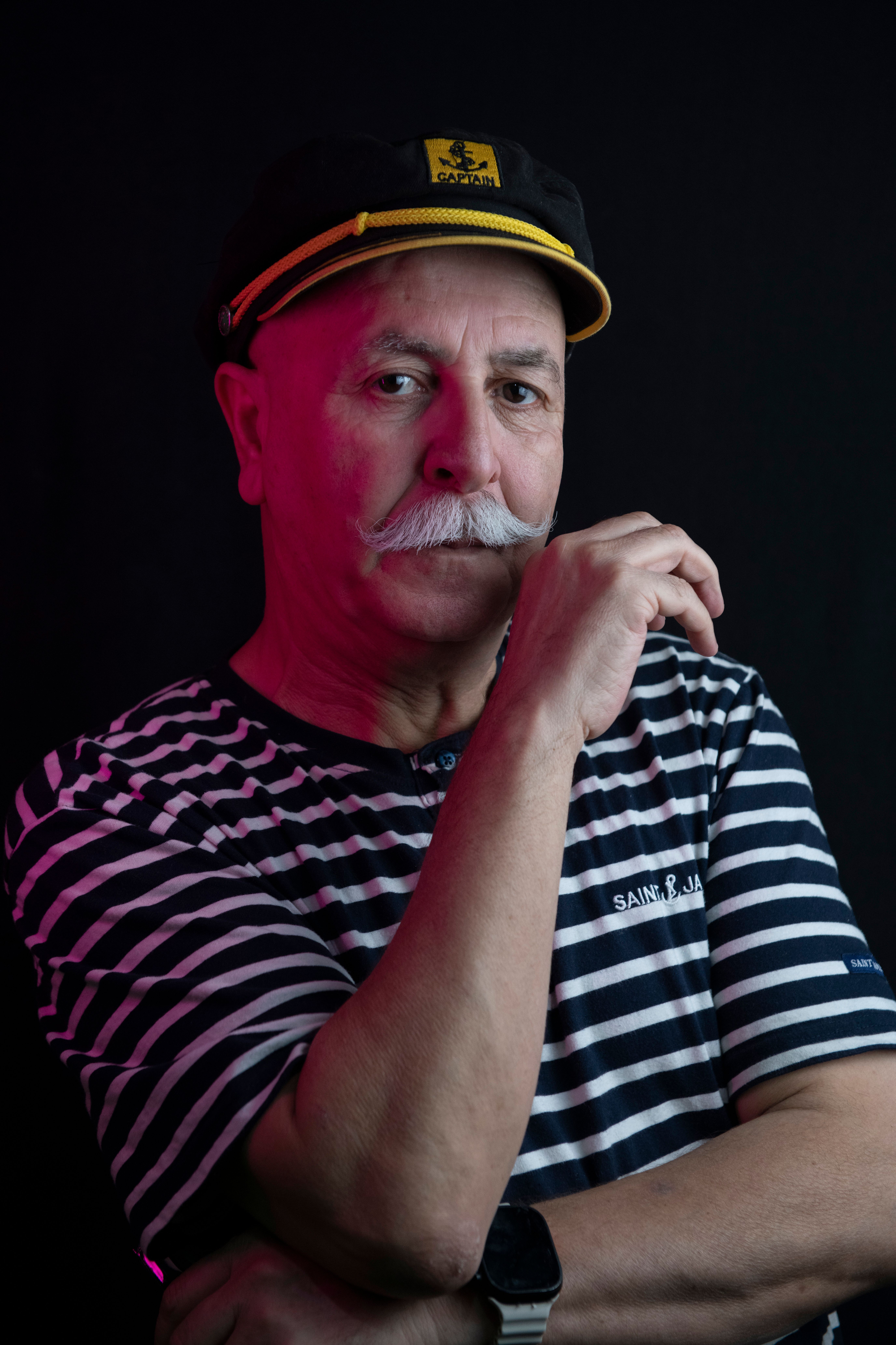 Portrait of a senior man with a mustache wearing a sailor hat and striped shirt.