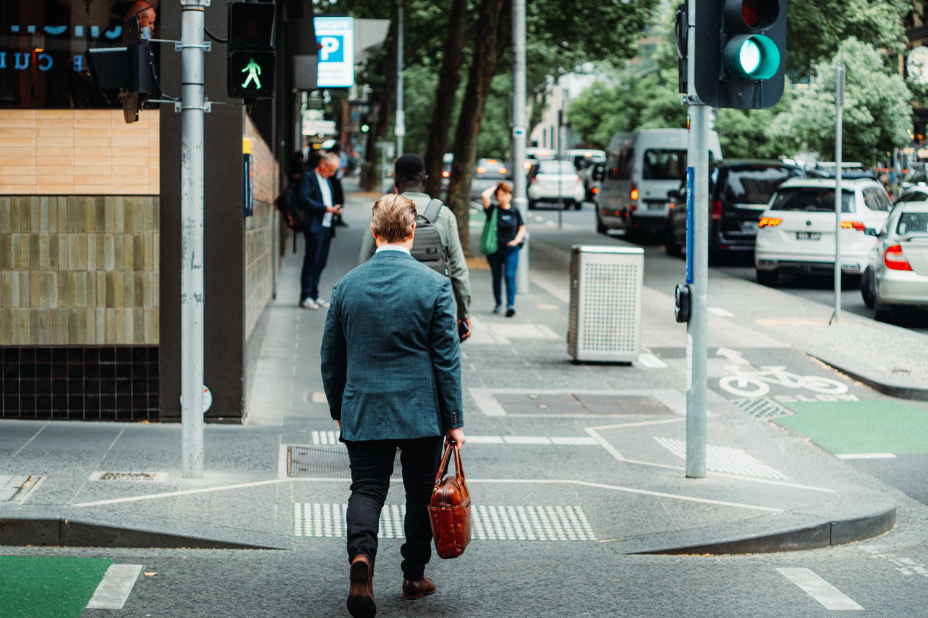 A businessman in a suit crossing the street in a busy urban area during the day.
