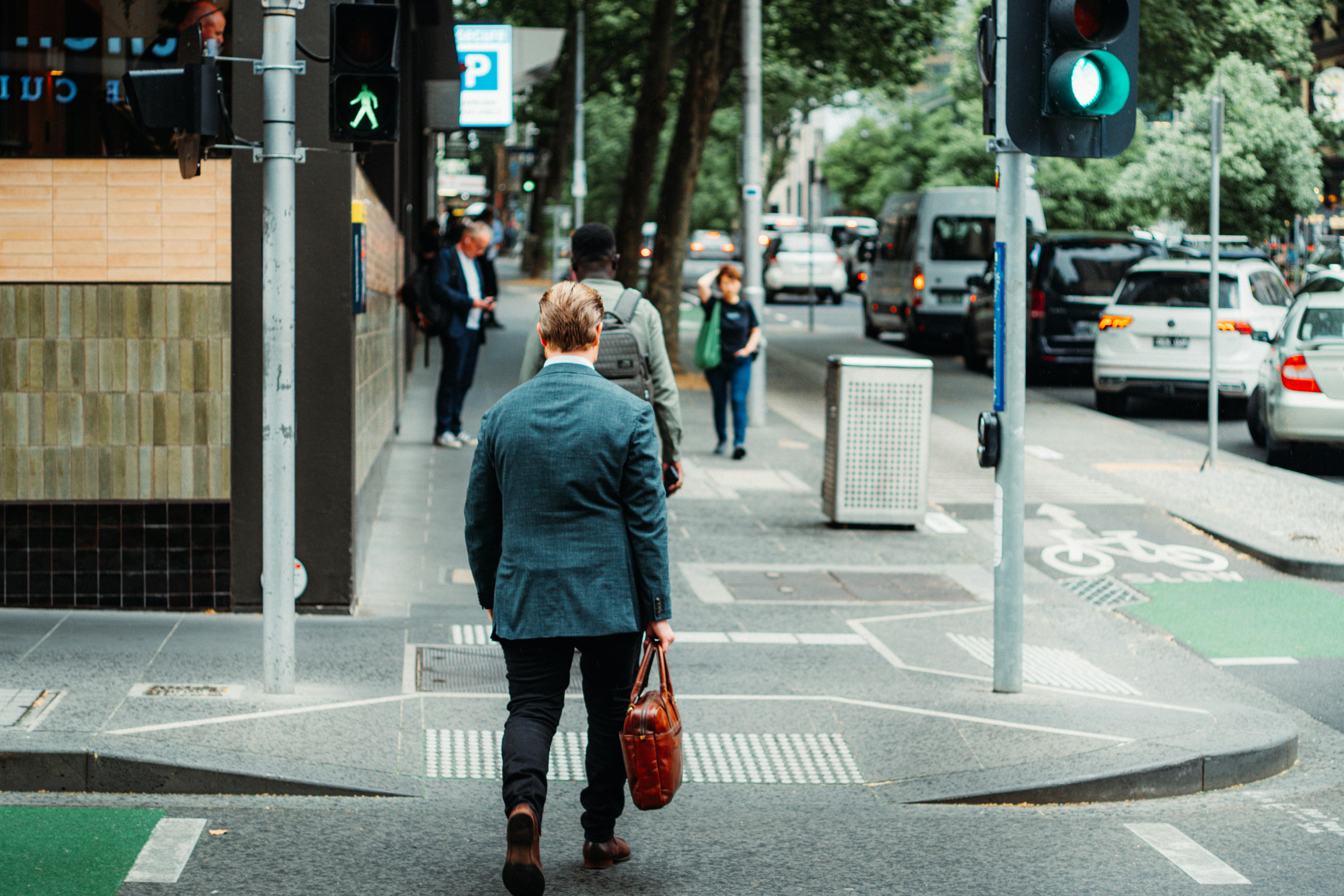 Free A businessman in a suit crossing the street in a busy urban area during the day. Stock Photo