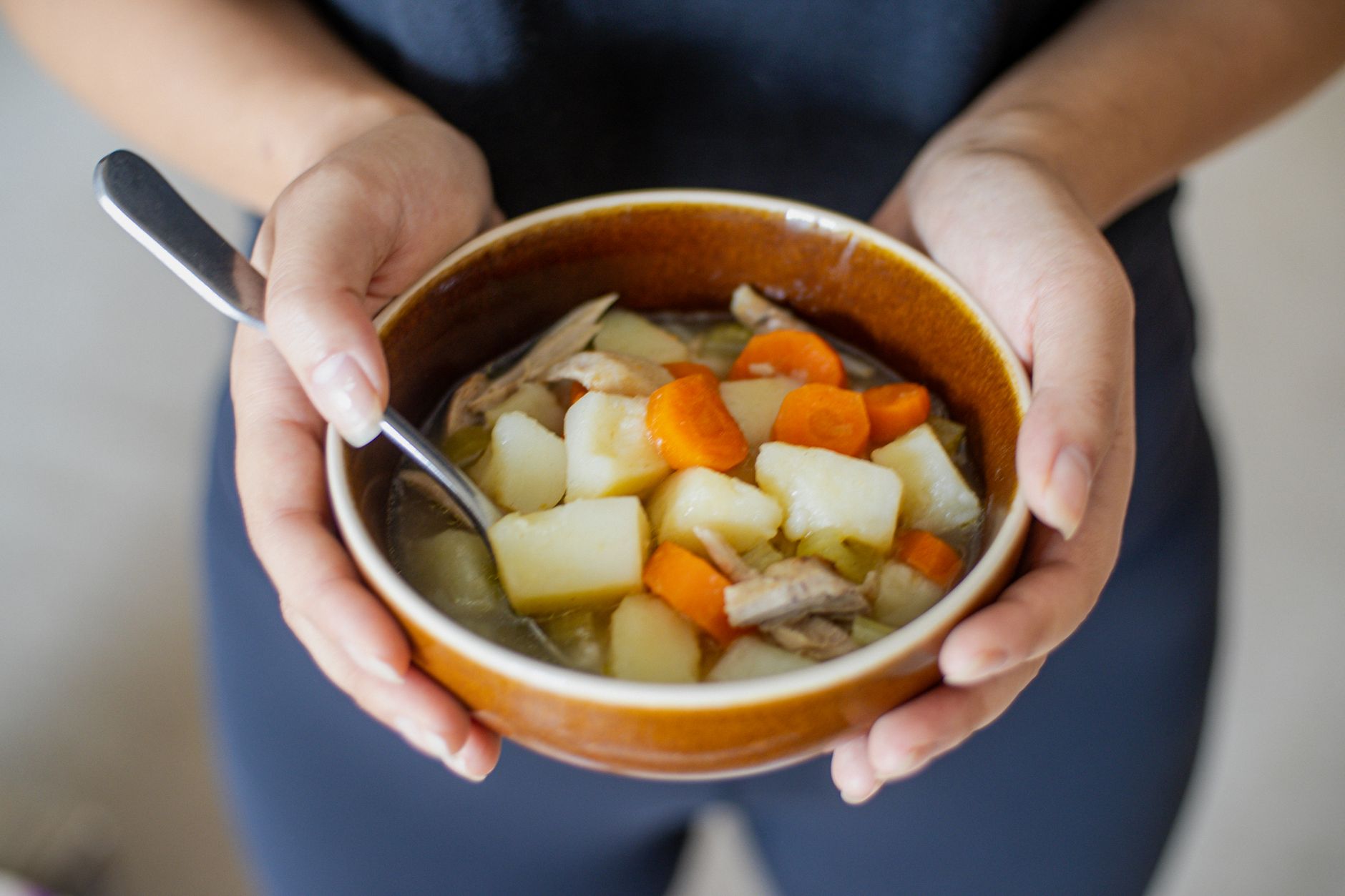 Creamy potato and carrot soup simmering in a saucepan with herbs