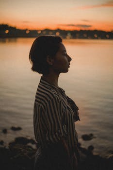 日落时分，湖畔一名女子的迷人轮廓，带着温暖的色调和宁静的氛围