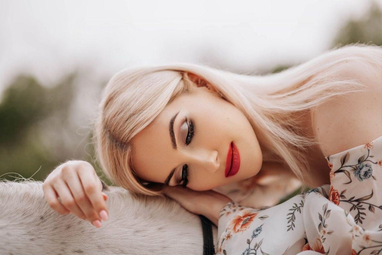 blonde woman in floral dress rests outdoors serene and relaxed
