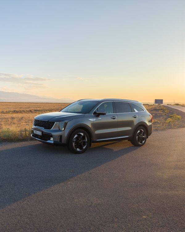 Free The left front view of the Kia Sorento stopped at sunset with the wasteland in the background. Stock Photo