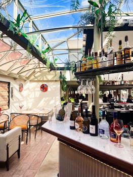 Elegant restaurant setting with bar, skylight roof, and lush greenery.