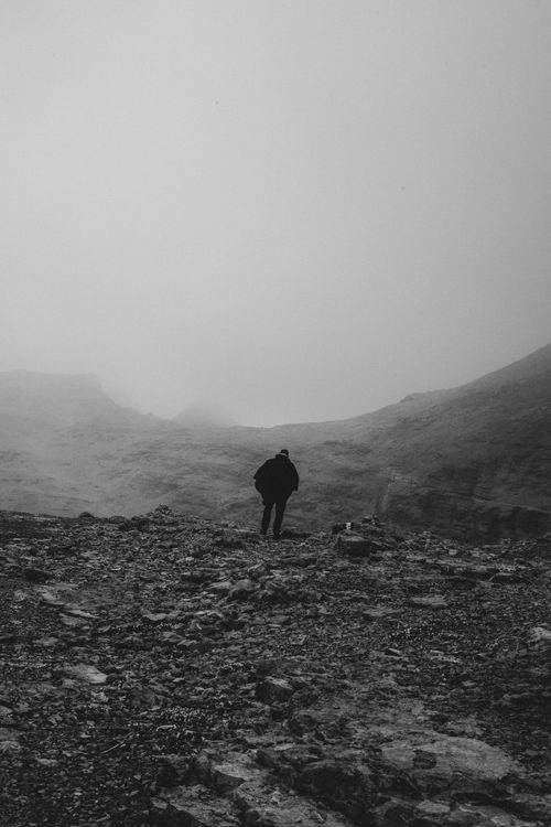 Free A lone hiker stands amidst a rocky, fog-covered mountain in Trentino-Alto Adige, Italy. Stock Photo