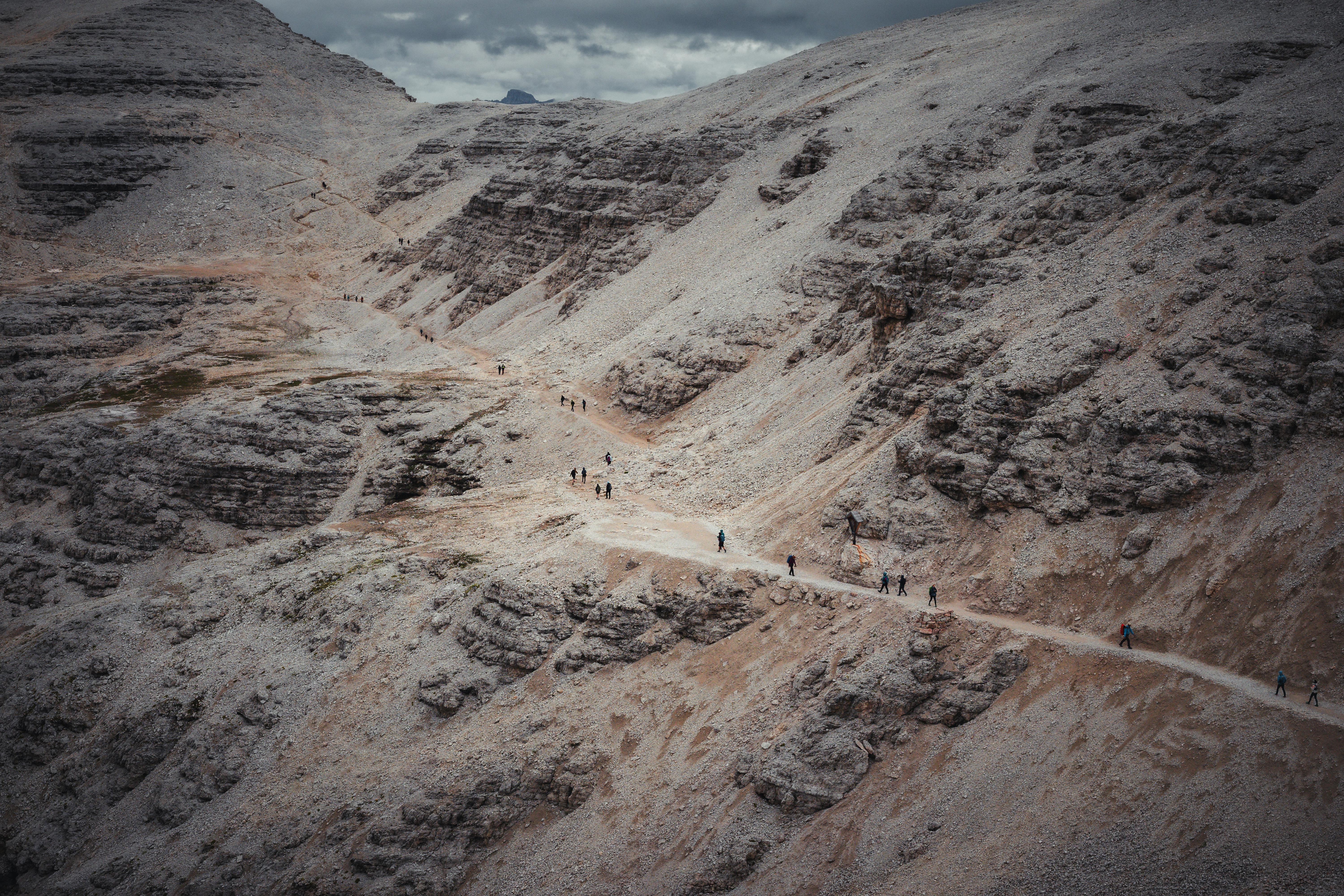 A group of hikers traversing a rugged mountain trail surrounded by dramatic rocky landscapes.